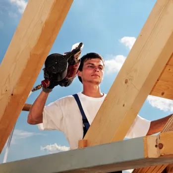 Close-up of a contractor using a power drill on a wooden board, highlighting precision remodeling services.